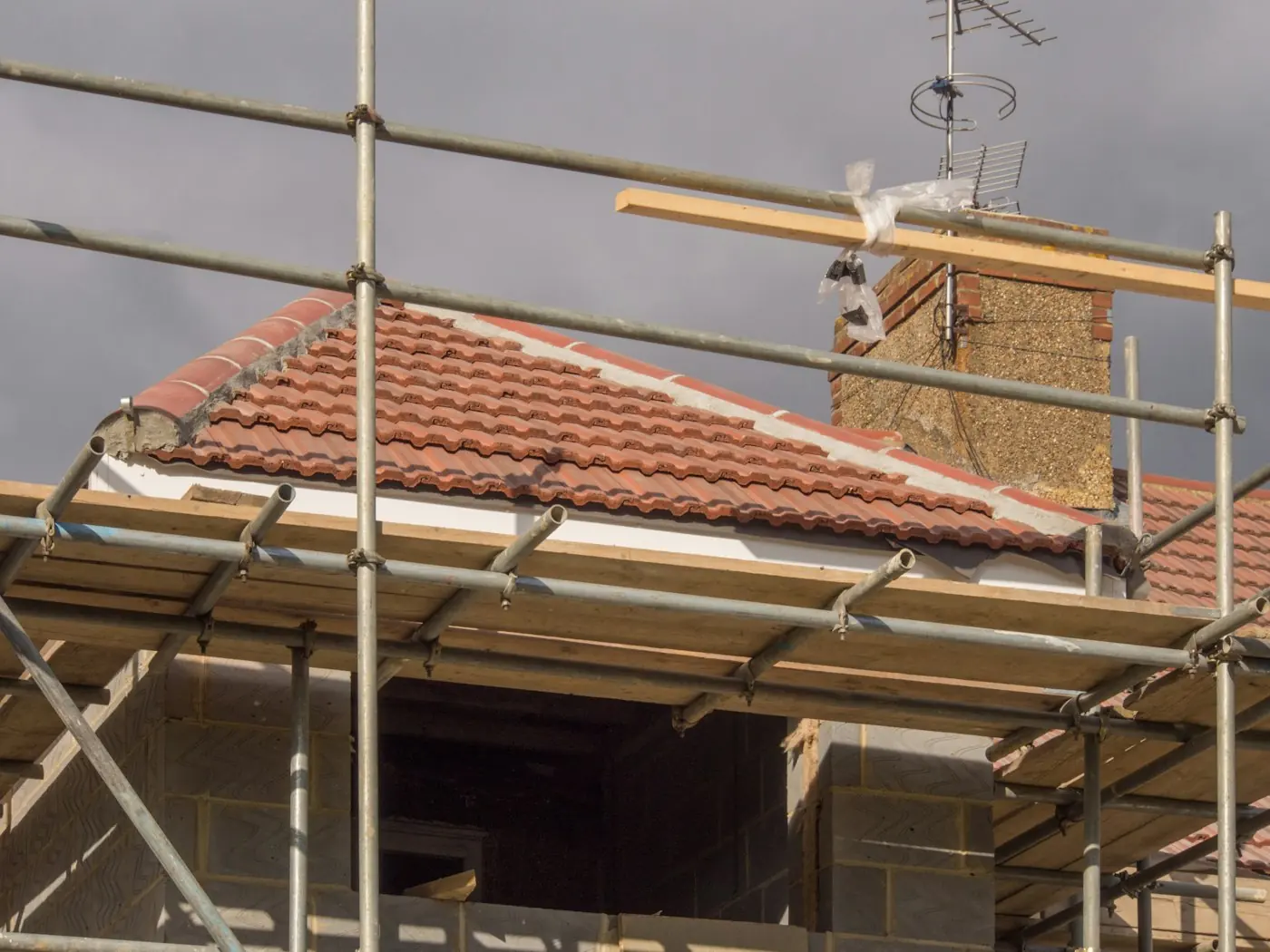 New clay roof tiles being laid on a scaffolded London house